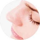 Close-up of a woman’s nose and closed eyes, highlighting smooth skin and refined features after rhinoplasty in Newport Beach.