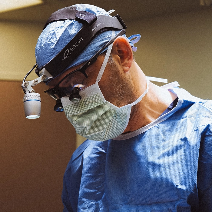 Dr. Batniji, facial plastic surgeon in Newport Beach, wearing blue scrubs and surgical mask ready for procedure.