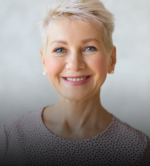 Smiling woman with short blonde hair after lower blepharoplasty.